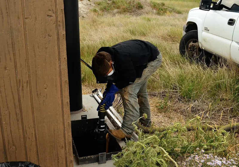 Pumping-a-septic-Tank-on-a-portable-bathroom Man empty a tank from a portable bathroom from Basin Septic and Rentals